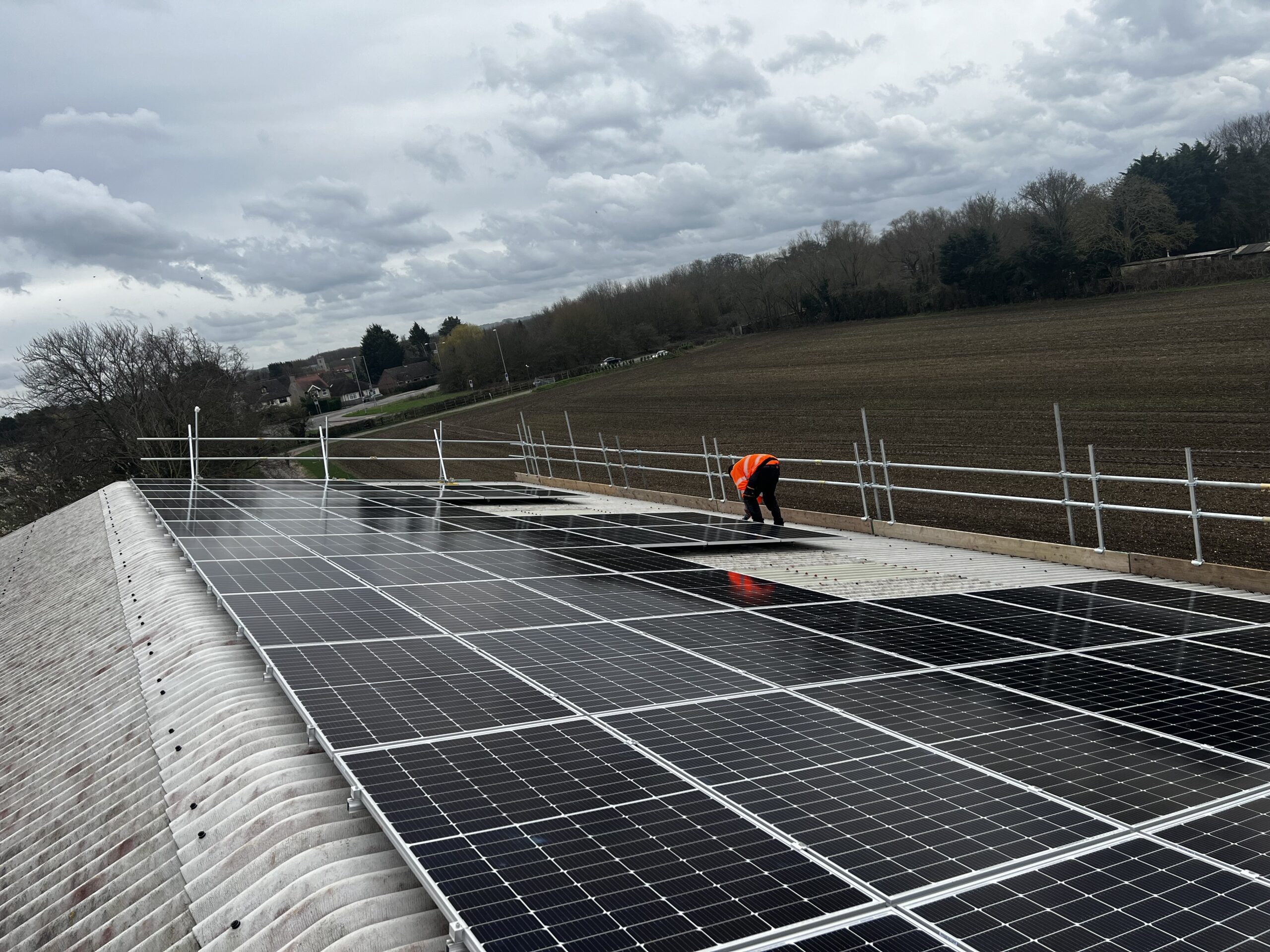 Technician installing commercial solar panels on a metal roof for renewable energy efficiency.
